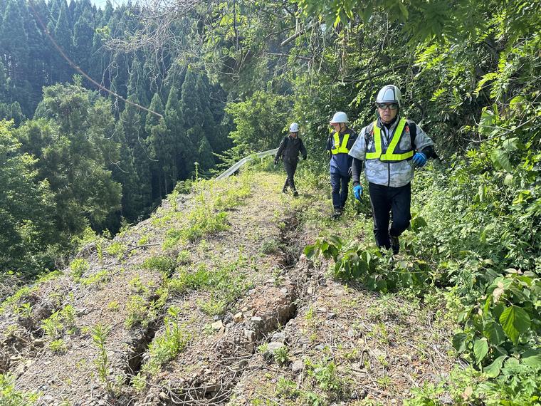 地割れの入った林道を歩いて被害を確認する3名